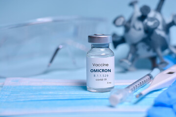 Two Bottle of Covid-19 vaccine to immunize from the Omicron Variant Coronavirus, syringe , face mask,body thermometer and protective glasses on blue background.The concept of medicine, healthcare