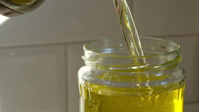 Hot drawn ghee butter pouring in glass jar.