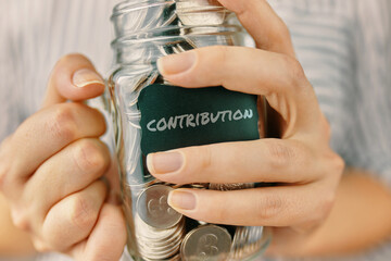 Contributions in glass jar. Woman holds a bottle of coins. Financial literacy.