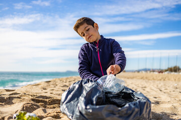 Little kid picking plastic on the beach. Recycling concept