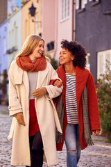 Woman Meeting Female Friend Walking Along Residential City Street In Fall Or Winter