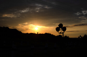 Silhouette of a railway crossing signals  against sunset sky	