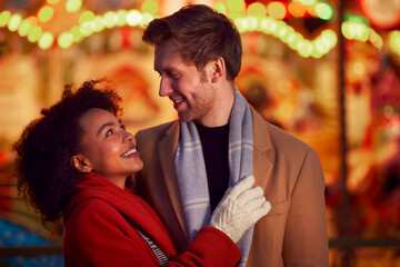 Couple Against City Lights Outdoors Wearing Coats And Scarves Enjoying Night Out Together