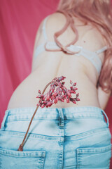 Body image of a real young woman wearing jeans and holding a exotic flower