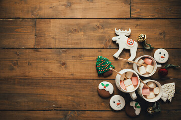 Obraz na płótnie Canvas Cocoa with marshmallow and gingerbread on wooden table. Flat lay style. Christmas festive decorations.