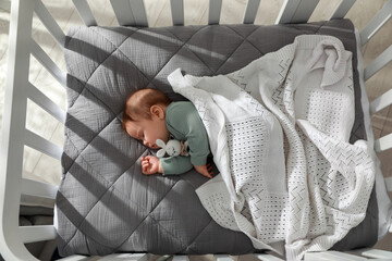 Cute little baby sleeping in crib, top view. Bedtime