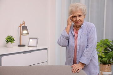 Senior woman with headache at home. Space for text