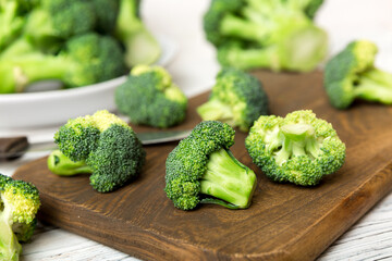 fresh green broccoli on wooden cutting board with knife. Broccoli cabbage leaves. light background. Flat lay