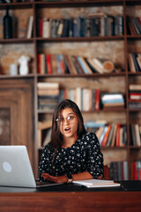 Young woman looks shocked after reading while works at the laptop