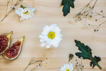 Beautiful daisy flower with  fig and leaves on a wooden background, above vantage point photography, close up 