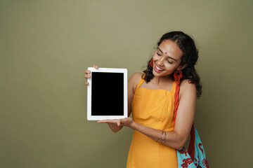 Young south asian woman in dress smiling while showing tablet computer