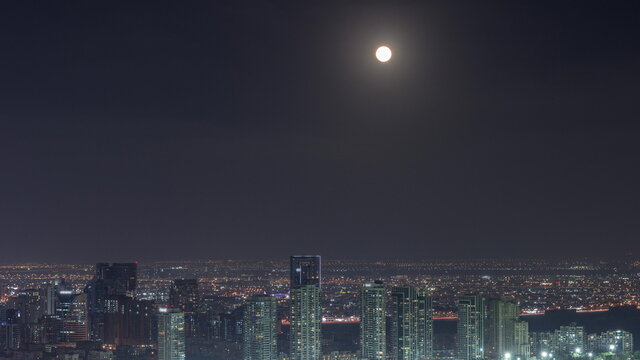 Moon rising over greens and al barsha heights district area night timelapse from Dubai marina. - Powered by Adobe