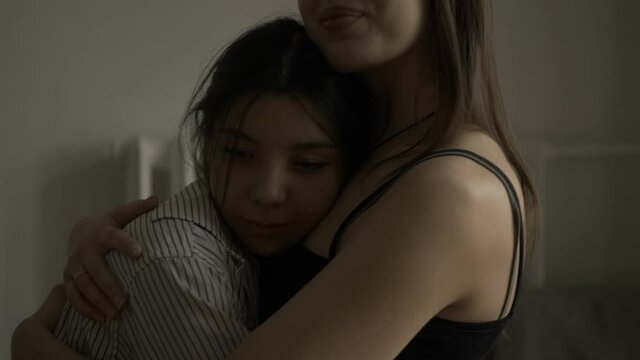 Two happy young women hug each other in a dark room. The women hug, smile and get excited. A woman of friendship, support and care. Filmed in cinematic style