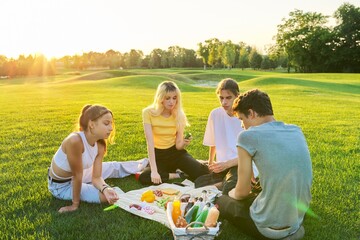 Teenagers having fun on a picnic in the park on lawn - obrazy, fototapety, plakaty
