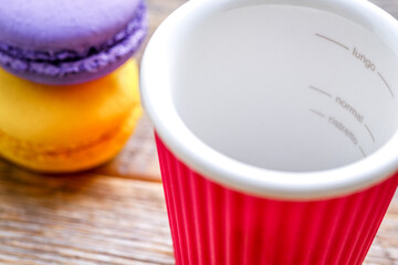 empty coffee cup on wooden table with multicolored macaroon