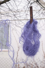 Mohair purple threads with a wooden clothespin on a cord. Wet gloomy day. Warm clothes concept. Vertical image. 