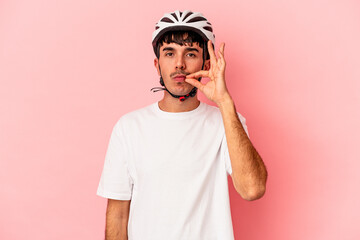 Young mixed race man wearing a helmet bike isolated on pink background with fingers on lips keeping a secret.