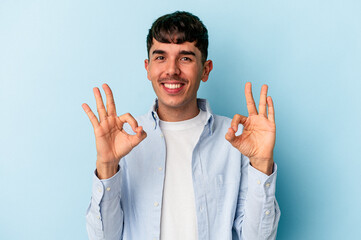 Young mixed race man isolated on blue background cheerful and confident showing ok gesture.