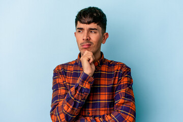 Fototapeta premium Young mixed race man isolated on blue background thinking and looking up, being reflective, contemplating, having a fantasy.