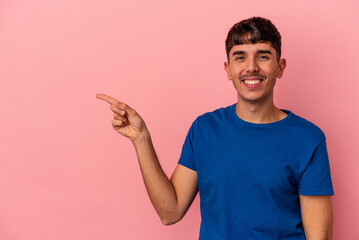 Young mixed race man isolated on pink background smiling cheerfully pointing with forefinger away.