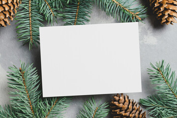 Fototapeta na wymiar Christmas or New Year greeting card mockup with fir tree branches and cones on grey background