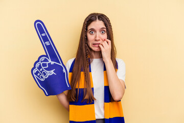 Young sports fan woman isolated on yellow background biting fingernails, nervous and very anxious.