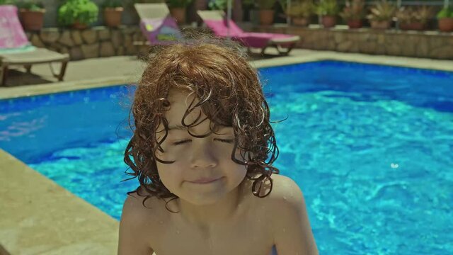Little boy having fun in the swimming pool.Happy cute little boy enjoying hot summer day at resort, having fun and smiling at camera