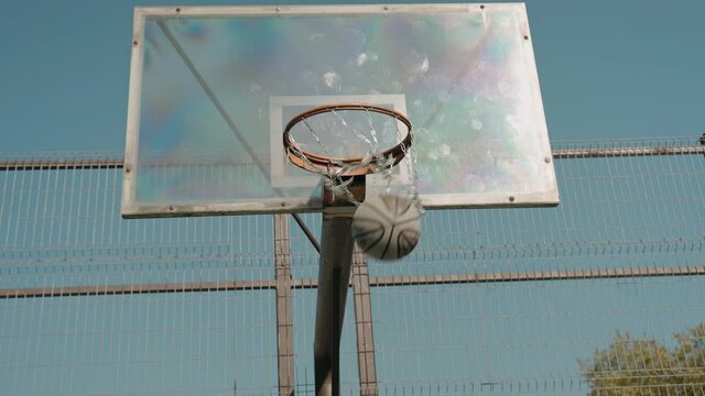 Man trains doing slam dunk alone on a street basketball court on a sunny day. Black man trains alone on a court in the park. High quality 4k footage