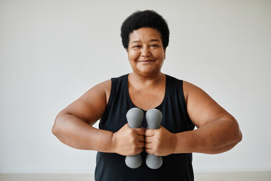 Minimal Waist Up Portrait Of Smiling Senior Woman Working Out Indoors Holding Dumbbells