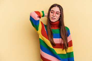 Young caucasian woman isolated on yellow background touching back of head, thinking and making a choice.