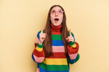 Young caucasian woman isolated on yellow background pointing upside with opened mouth.