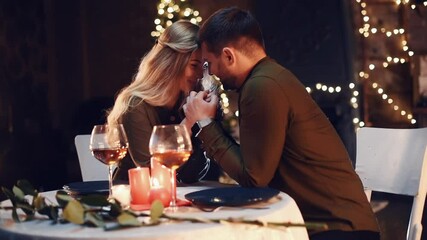 Holding each other by the hands. Sweet lovely couple having a romantic dinner indoors together - Powered by Adobe