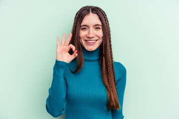 Young caucasian woman isolated on green background cheerful and confident showing ok gesture.