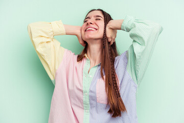 Naklejka premium Young caucasian woman isolated on green background feeling confident, with hands behind the head.