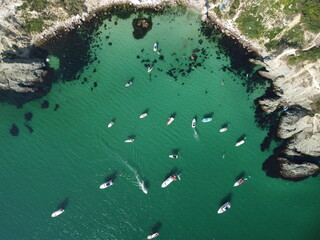 Aerial panoramic view of seascape with crystal clear azure sea and rocky shores. Yachts in a beautiful lagoon on backdrop of rocks. The concept of an ideal destination for summer travel and vacation.