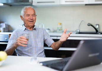 Naklejka na ściany i meble Old man communicating via internet at home