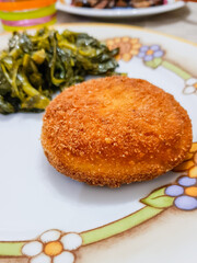 Pane tagliato in forma rotonda, ripieno di formaggio, impanato e fritto con contorno di verdure