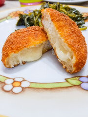 Pane tagliato in forma rotonda, ripieno di formaggio, impanato e fritto con contorno di verdure