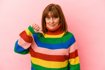 Middle age caucasian woman wearing a multicolor sweater isolated on pink background showing a dislike gesture, thumbs down. Disagreement concept.