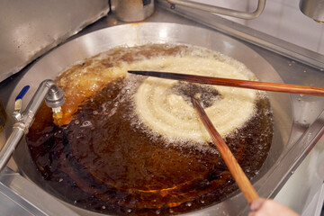 Cook the dough for the churros or porras in boiling hot oil in a frying pan. Typical Spanish breakfast
