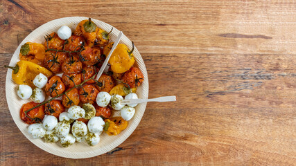 Plate of grilled tomatoes, peppers and mozzarella balls over wooden background with copy space.