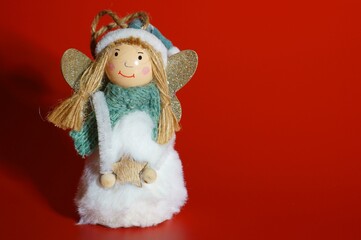 Toy Christmas angel close-up on a red background. New Year's characters.