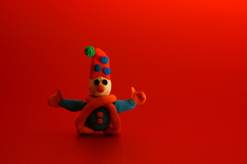 A toy snowman made of plasticine on a red background. Holiday photo.