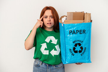 Young caucasian woman recycled paper isolated on white background showing a disappointment gesture with forefinger.