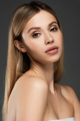 Naklejka premium sensual woman with bare shoulders and perfect skin looking at camera isolated on grey