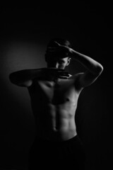 Obraz na płótnie Canvas Black and white portrait a slender athletic man on a dark background.