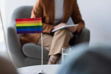 cropped view of psychologist near small lgbt flag and blurred homosexual patients