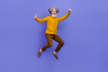 Fototapeta na wymiar Full length body size view of attractive cheery gray-haired man jumping showing thumbup isolated over bright violet purple color background