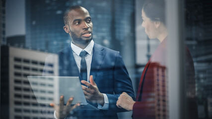 Portrait of Successful Corporate CEO and Investment Manager Talking, Using Laptop Computer while Standing in City Office. Stock Market Businesspeople Negotiate e-Commerce Software Purchase