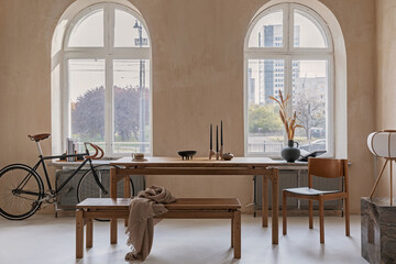 Stylish interior design of spacious dining room with wooden dining table, bench and beautiful personal accessories. Modern home decor. Structure wall. Rustic minimalitic inspiration. Template.